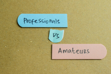 Concept of Professionals vs Amateurs write on sticky notes isolated on Wooden Table.