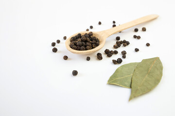 dried bay leaf and black pepper on a white background.