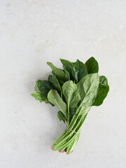 Bunch of fresh green spinach, leaves and stems on light-colored granite countertop, high angle view with copyspace.