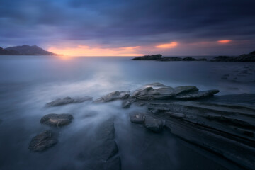 sunset in cold tones with water between the rocks in the foreground on Lastron beach in Muskiz,...
