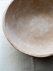 An empty ceramic tile on a white linen tablecloth. Close-up. Flat layout, top view. Blur. Selective focus. A place to record. The plate is brown, natural color. Natural clay.