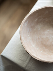 An empty ceramic tile on a white linen tablecloth. Close-up. Flat layout, top view. Blur. Selective focus. A place to record. The plate is brown, natural color. Natural clay.