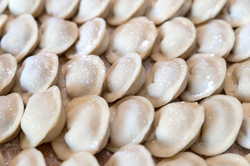 The raw dumplings were placed on a wooden cooking board, sprinkled with flour. The filling is...