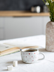 Black coffee in a white mug on a saucer on a grey table. Instant coffee.