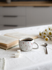 Morning coffee. There is a book on the table, mug of coffee.