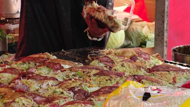 TOKYO, JAPAN : View of cooking OKONOMIYAKI (Japanese style pancake) at the street food stall. Japanese food and summer festival concept video.