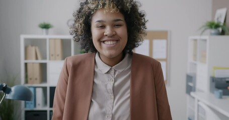 Portrait of emotional African American businesswoman smiling then making serious face changing mood in office. Business and emotion concept.