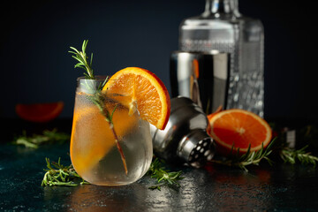 Cocktail gin tonic with ice, orange, and rosemary.