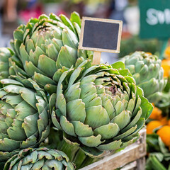 Fototapeta premium Fresh artichokes for sale at a local farmers market with a price sign
