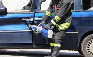 Firefighter using hydraulic shears to pry open the door of a wrecked car