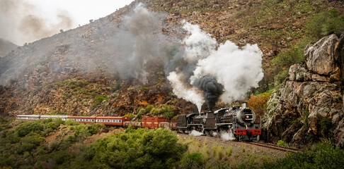 Steam train steaming through mountain pass