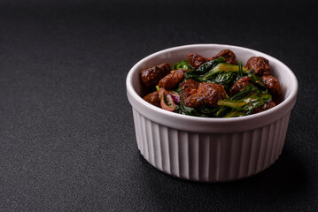 Delicious warm salad with pieces of meat, spinach, tomatoes, salt, spices and herbs