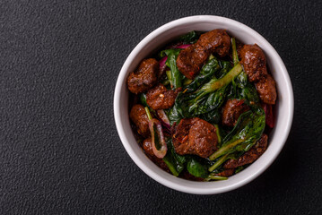Delicious warm salad with pieces of meat, spinach, tomatoes, salt, spices and herbs