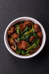 Delicious warm salad with pieces of meat, spinach, tomatoes, salt, spices and herbs