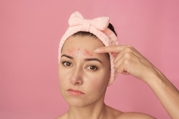 A young Caucasian brunette woman with a pink headband looks at the camera and frustratedly shows...