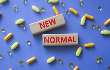New normal symbol. Wooden blocks with words New normal. Beautiful purple background with pills....
