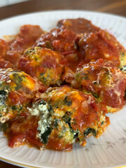 Malfatis de ricota y espinaca con tuco de salsa de tomate, estofado y salchicha.