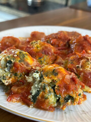 Malfatis de ricota y espinaca con tuco de salsa de tomate, estofado y salchicha.