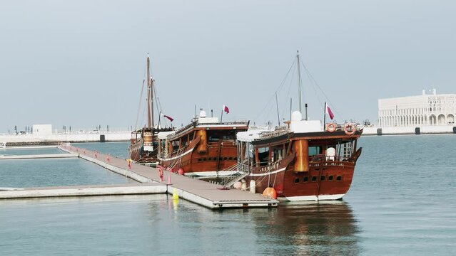 Perspective view of a traditional wooden dhow in foreground with seafront of Doha Bay and City Gallery at background. Capital of Qatar, Middle East. Tourquoise Persian Gulf.
