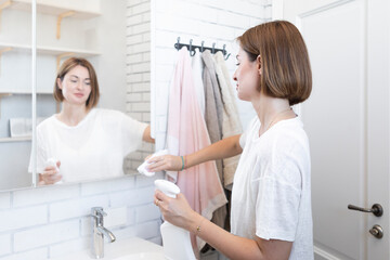 Young housewife cleaning mirror in the bathroom	