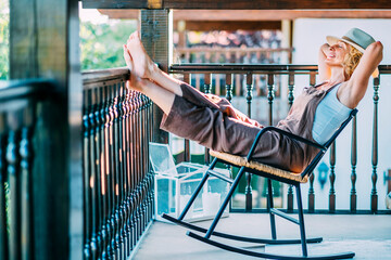 A woman is relaxing on a rocking chair on a balcony.