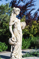 Ukraine, Volodarka town, Sakura Island landscape park. Statue of woman with two jugs on tree...
