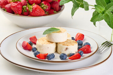 Stack of four cheesecakes on a plate with berries, blueberries, strawberries and cherries.