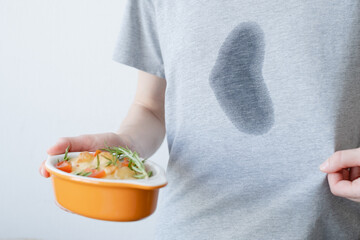 An unrecognizable woman holding a salad while the other hand showing a dirty stain of spilled oil...