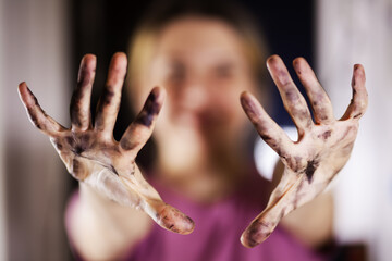 Creative close-up of an artist's paint-stained hands, stretching towards the camera in a blurred studio setting, expressing artistic passion and dedication.