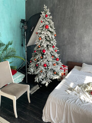 Christmas tree with gifts in the interior of a photo studio with a bed