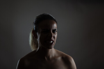 Intense portrait of a young woman expressing anger or frustration with a dark background