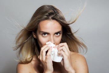 Young woman with flowing hair using a tissue, expressing subtle emotions