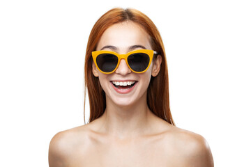 Vibrant portrait of a cheerful young woman with red hair wearing stylish yellow sunglasses,...