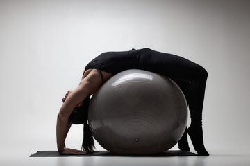 Young woman displaying flexibility and strength in a yoga pose with a fitness ball