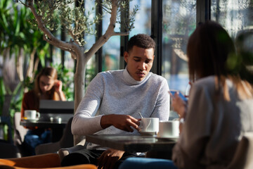 Two friends in a restaurant talking smiling and drinking tea.