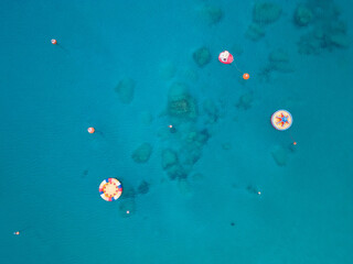 Aerial top down view of watersport playground area. Colorful objects floating on clear blue sea at Konnos beach, Cyprus.