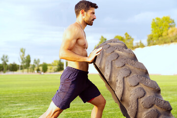 A man is lifting a tire on a field