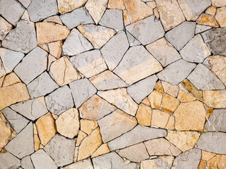 Background of a beige and gray Fieldstone mosaic wall. Old stone wall texture. Abstract stone pattern, home decoration.