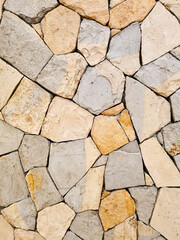 Background of a beige and gray Fieldstone mosaic wall. Old stone wall texture. Abstract stone pattern, home decoration.