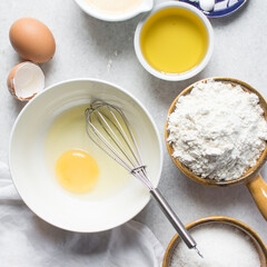 Overhead view of organic raw eggs in a white mixing bowl for baking and cooking, flatlay of egg in a white ceramic bowl