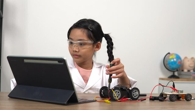 Asian girl assembling model car and programming remote control,engaging in STEM activities,developing engineering skills,learning robotics,exploring technology,enhancing creativity through hands-on pr