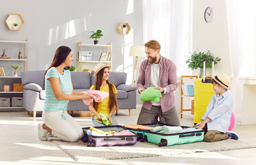 Happy young parents with two kids boy and girl packing suitcases preparing for summer vacation trip...