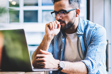 Thoughtful it developer thinking about fixing software bugs on netbook downloading files from network,contemplative male student watching tutorial on web site learning online via laptop computer