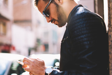 Cropped image of hipster guy using smartphone for searching cafes in application standing...