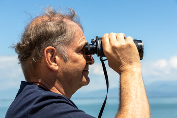 Mann mit Fernglas bei der Vogelbeobachtung