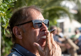 Mann mit Sonnenbrille, der eine Zigarillo raucht