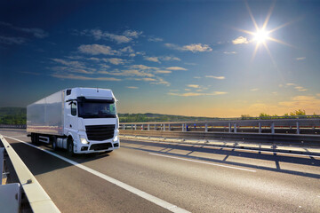 Large Transportation Truck on a highway road through the countryside at sunset