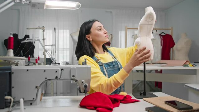 Fashion designer experiments and creates in his workshop using a mannequin as a model for fitting. The couturier creates unique fashionable handmade clothes. Medium shot. Slow motion.
