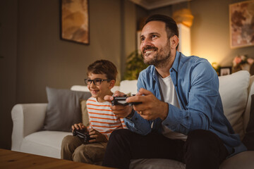 Adult caucasian father and son play video games with joystick at home