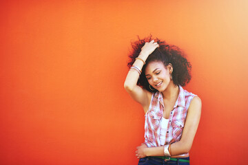 Girl, happy and confidence in fashion by wall with casual style, trendy outfit and mockup space on orange background. Woman, person or thinking in city with streetwear, afro and pride in edgy clothes